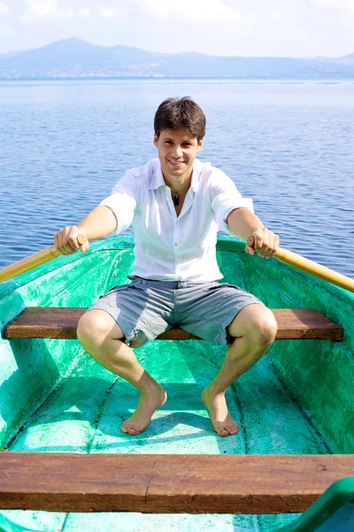 Hombre guapo en barco de madera verde remando — Foto de Stock