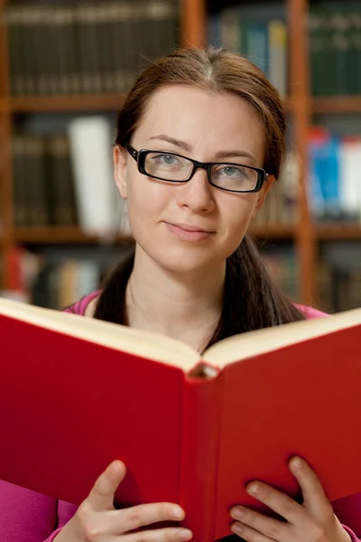 Meisje in bibliotheek met boek — Stockfoto