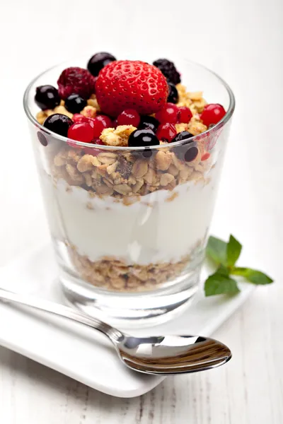 Йогурт з мюслі та ягодами у маленькому склянці — стокове фото