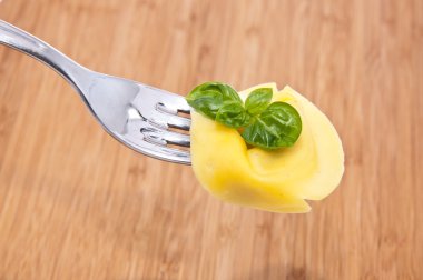 Tortellini on a fork with wooden background clipart