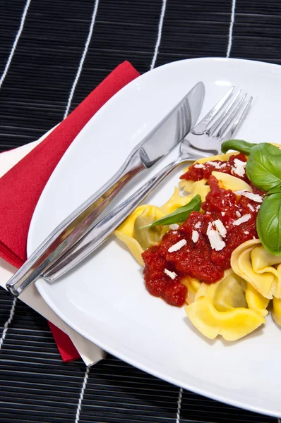 A fekete háttér ellenében lemez tortellini — Stock Fotó