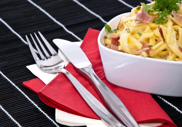 Cheese Spaetzle with cutlery (on black) — Stock Photo, Image