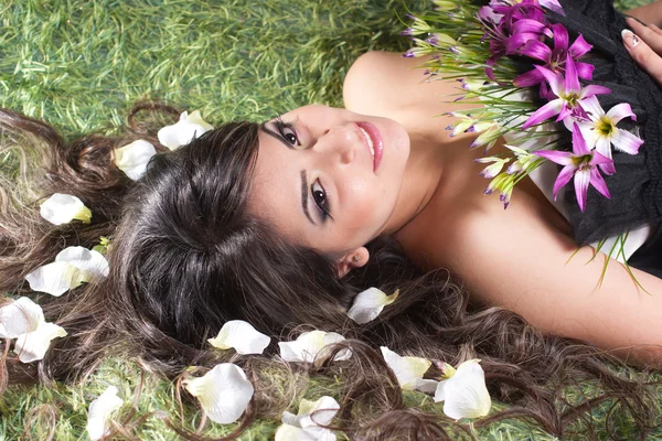 Молодая женщина лежит в лепестках цветов — стоковое фото