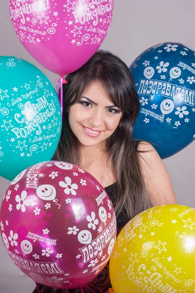 Η νεαρή γυναίκα, κρατώντας πολύχρωμα μπαλόνια Εικόνα Αρχείου