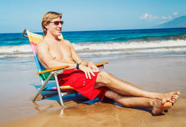 Genç adam sahilde rahatlatıcı — Stok fotoğraf