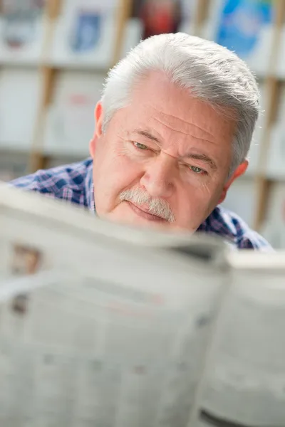 Homem idoso com bigode papel de leitura na biblioteca — Fotografia de Stock