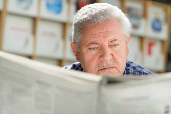 Starší muž s knírkem, čtení knihy v knihovně — Stock fotografie