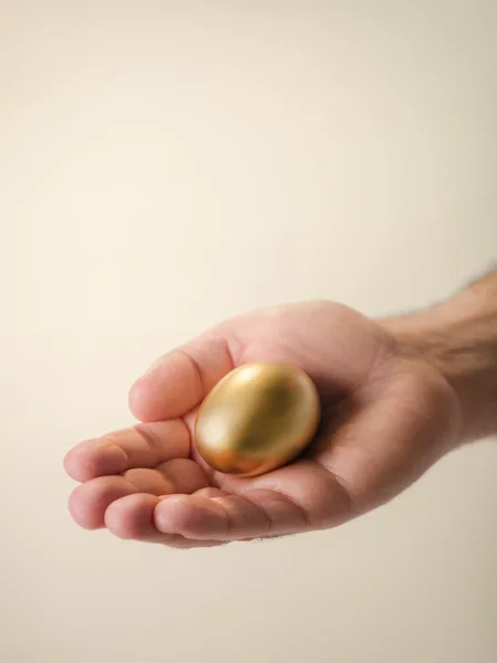 Man showing golden eggs, symbol of money saving — Stock Photo, Image