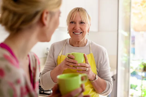Moeder en dochter praten, drinken koffie in keuken — Stockfoto