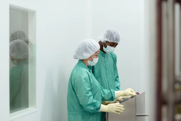 Personal och forskare kontrollera utrustning i biotekniska industrin — Stockfoto