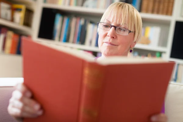 Feliz mujer mayor con gafas libro de lectura en casa —  Fotos de Stock