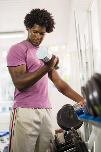 Młody czarny człowiek biorąc wagi od regału w siłowni — Zdjęcie stockowe