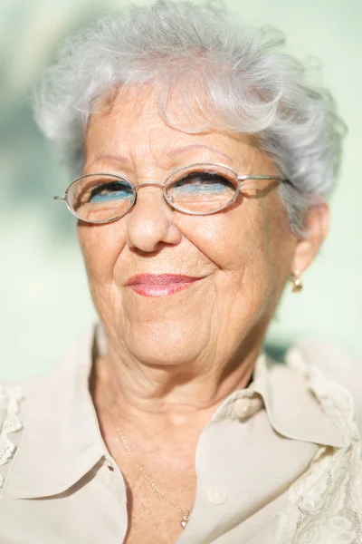 Stara kobieta z okularów, uśmiechając się i patrząc na kamery — Zdjęcie stockowe