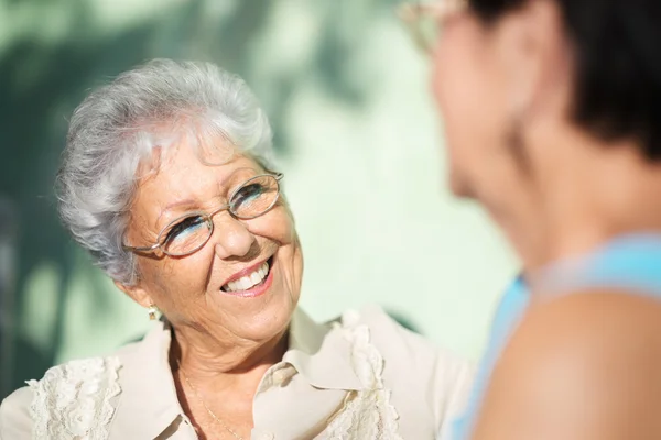 Старые друзья, две счастливые пожилые женщины разговаривают в парке — стоковое фото