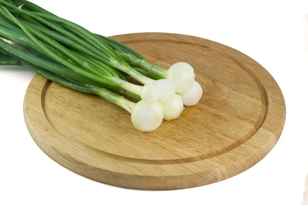 Cebolas verdes em uma placa de cozinha de madeira — Fotografia de Stock