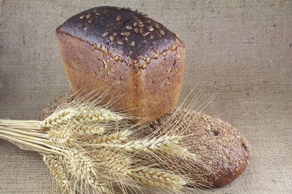 Dva bochníky chleba a pšenice na plátně — Stock fotografie