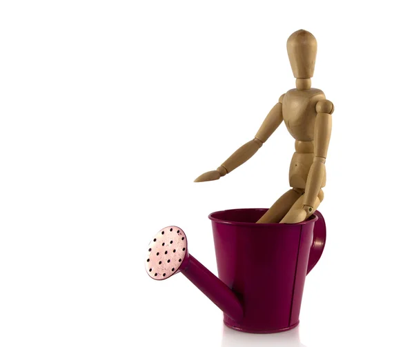 Wooden puppet on pink watering can — Stock Photo, Image