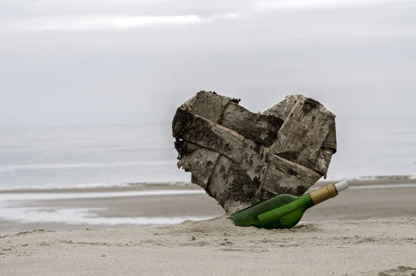 Mensaje en una botella y un corazón perdido en la playa —  Fotos de Stock