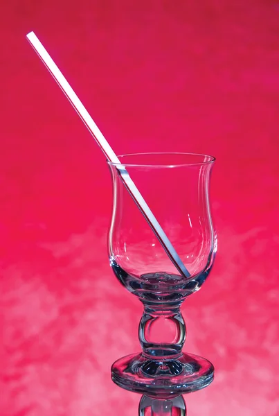 Пустой стакан с соломинкой на красном фоне — стоковое фото
