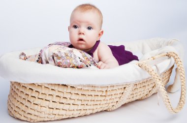 Little sweet girl a baby lying on a beautiful cushion in a wicke clipart