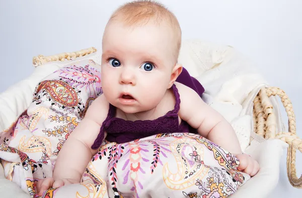 Midesi sepet içinde yatarken şirin bebek şaşırmış görünüyor — Stok fotoğraf