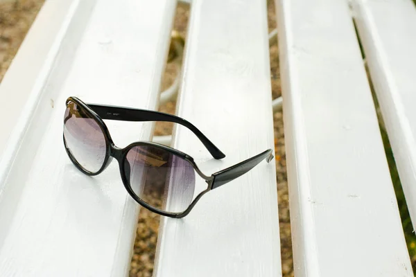 Солнечные очки на белой скамейке — стоковое фото