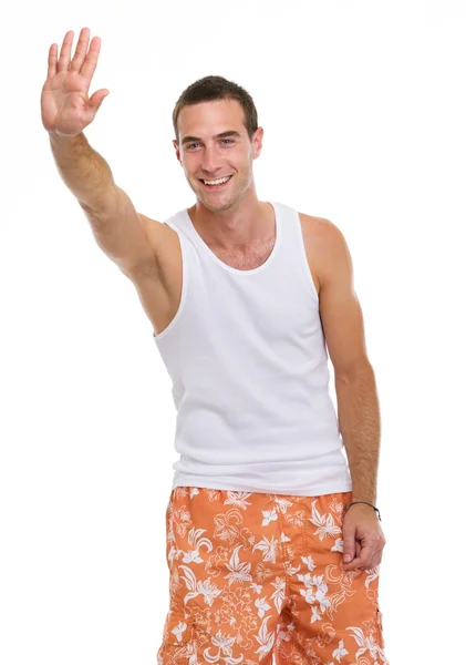 På semester leende ung man i shorts och t-shirt salutera — Stockfoto