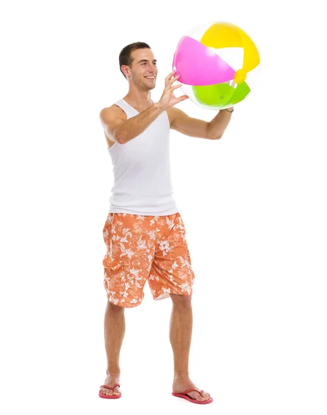 Odpoczynek na wakacje szczęśliwy młody człowiek gra z piłka plażowa — Zdjęcie stockowe
