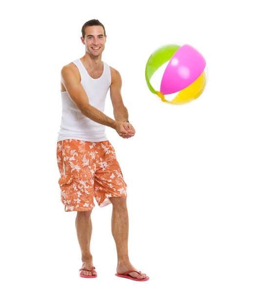У відпустці щасливий молодий чоловік грає у волейбол з пляжним м'ячем — стокове фото