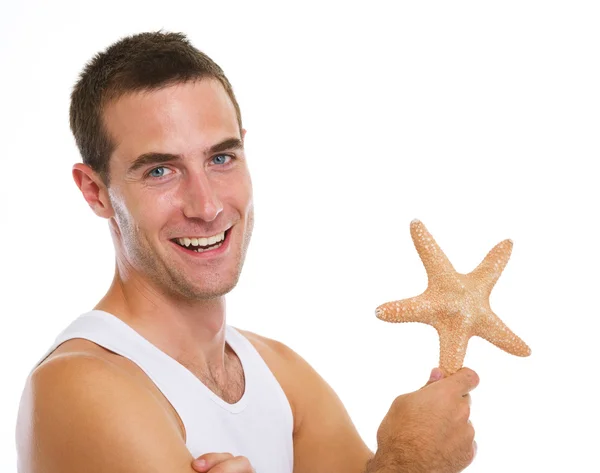 Portrait of on vacation smiling young man with sea star — Stock Photo, Image