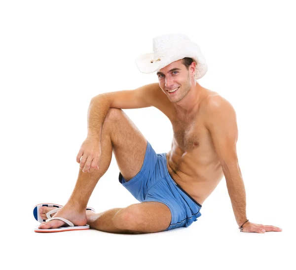 Mosolygó fiatal ember kalapban ülő földre — Stock Fotó