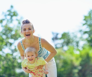 Happy mother and baby playing outside clipart