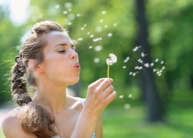 Young woman blowing away dandelion clipart