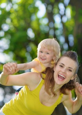 Happy baby girl piggybacking mother clipart