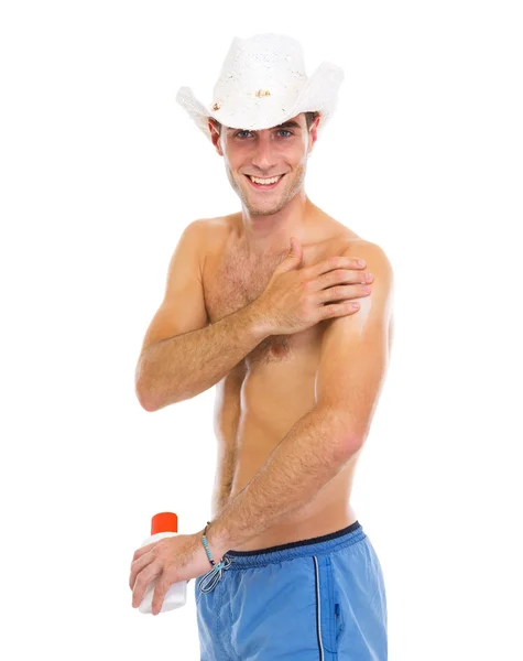 Szczęśliwy człowiek w kapeluszu, stosując krem do opalania na ramię — Zdjęcie stockowe