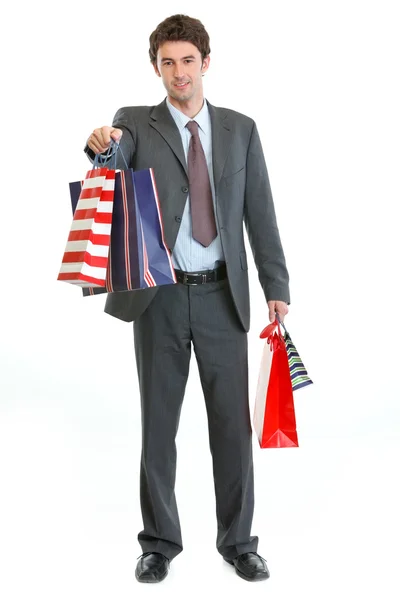 Uomo in giacca e cravatta stretching mano con shopping bags — Foto Stock