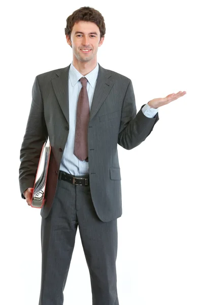 Modern businessman holding folder and showing something on empty — Stock Photo, Image