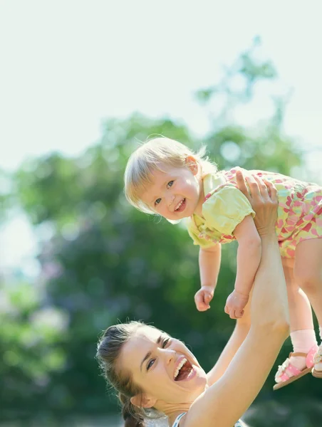 Smiling mother rising baby — Stock Photo, Image