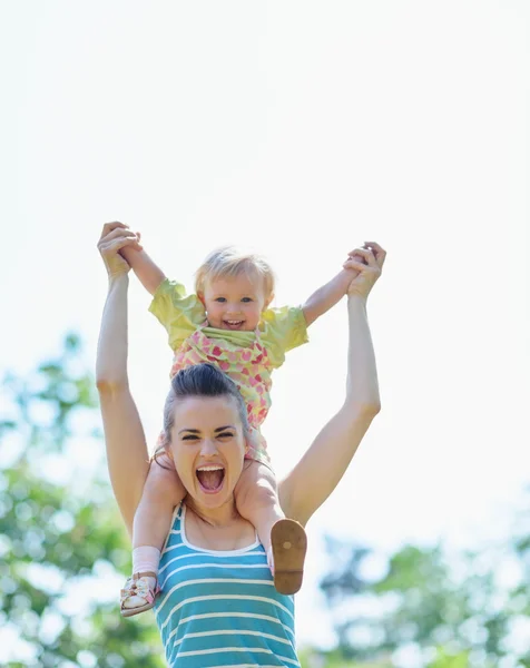 Happy mother with baby sitting on shoulders — Stock Photo, Image