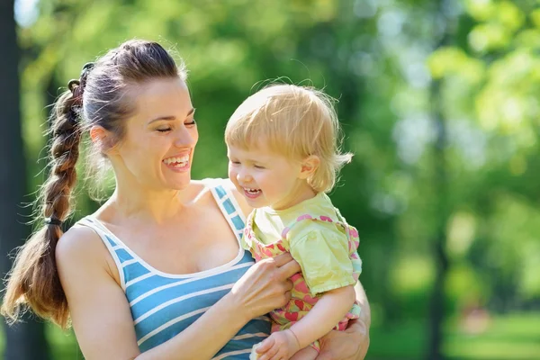Happy mother tickling baby outside — Stock Photo, Image