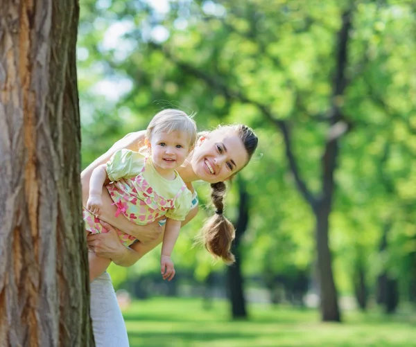 Happy mother and baby looking out from tree — Stock Photo, Image
