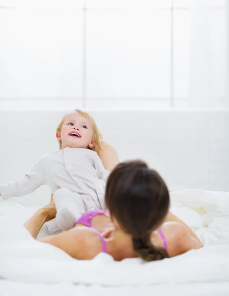 Moeder spelen met baby op bed — Stockfoto