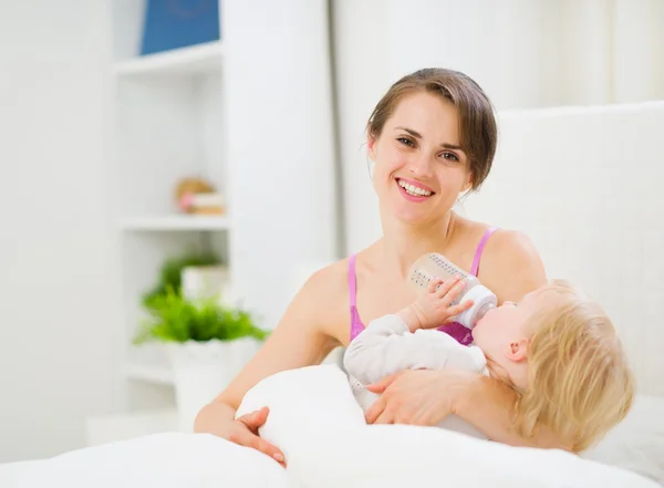 Mother feeding kid in bed — Stock Photo, Image