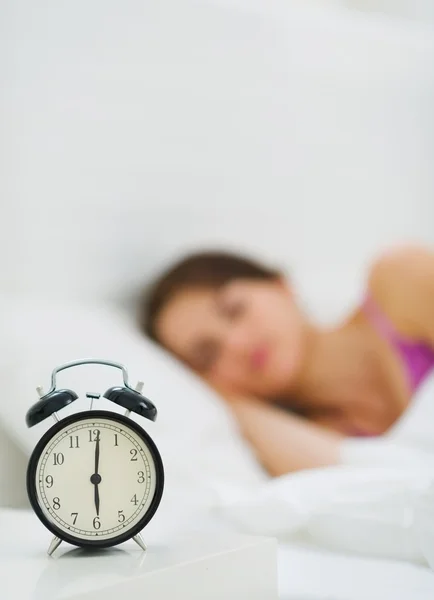 Çalar saat tablo ve arka planda uyuyan kadın — Stok fotoğraf