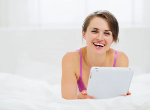 Femme souriante couchée au lit et utilisant une tablette PC — Photo