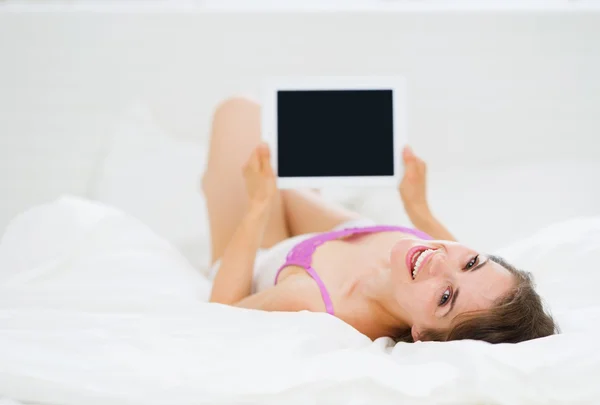 Femme souriante couchée au lit et utilisant une tablette PC — Photo