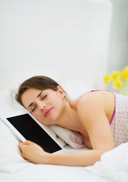 Счастливая девушка спит обнимая планшет PC — стоковое фото