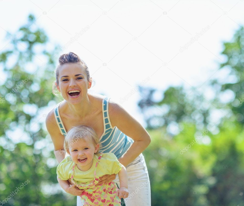 Happy mother and baby playing outside