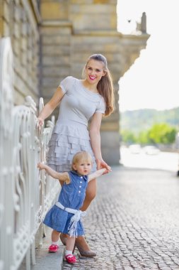 Full length portrait of mother and baby in city clipart