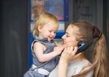 Mother and baby talking phone in city clipart